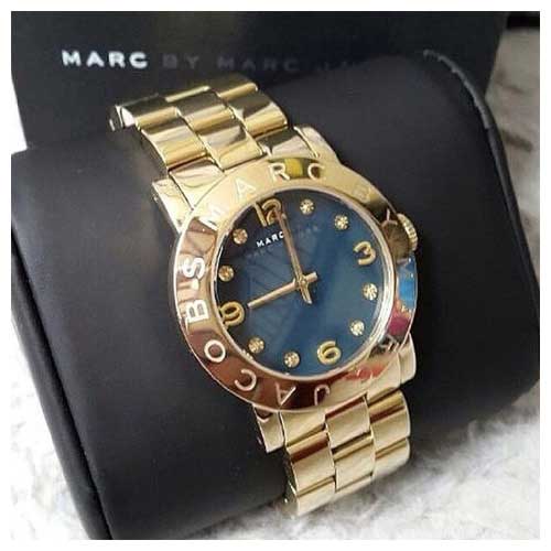 Marc By Marc Jacobs Amy watch angle view showing gold bracelet and black dial on box